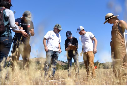 students and faculty looking at instrument panel on grass outside